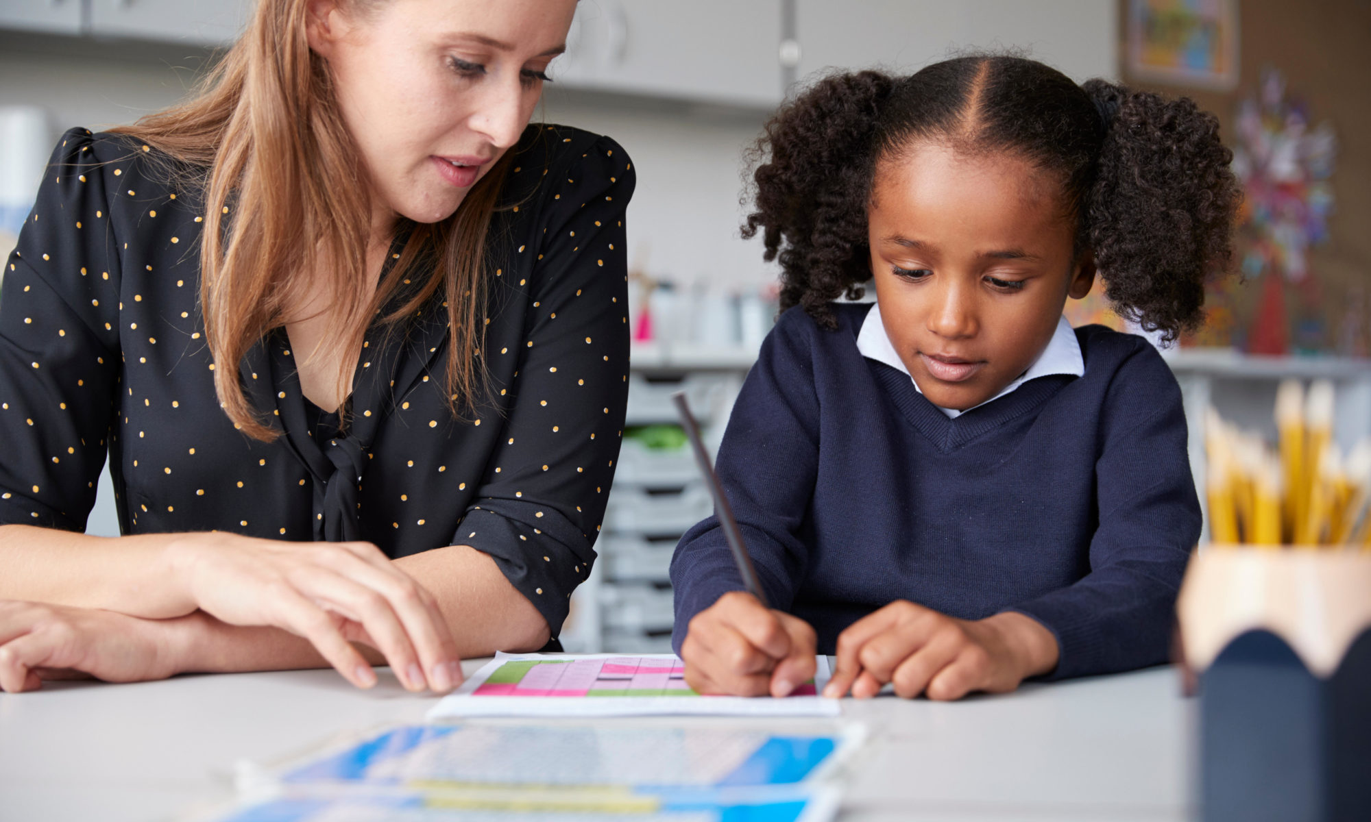 sea scale primary school teacher working one on one with a schoolgirl in a classroom